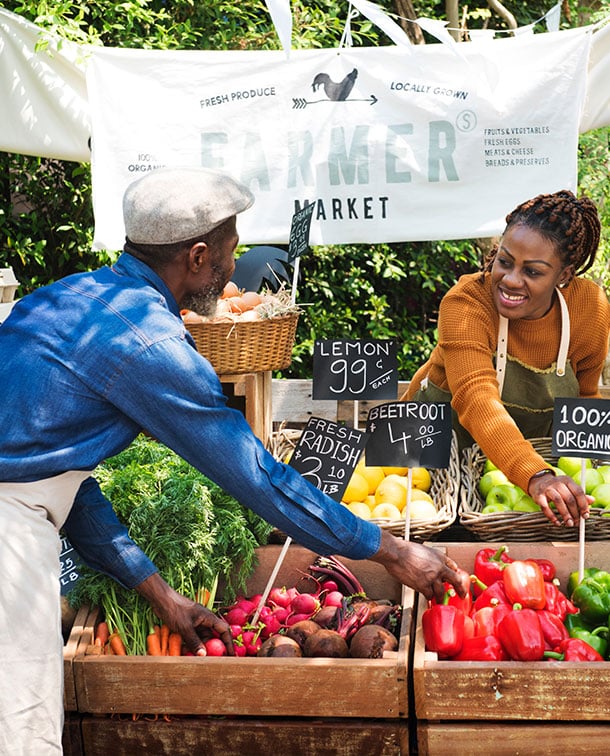 Two vendors working at a farmers market stand